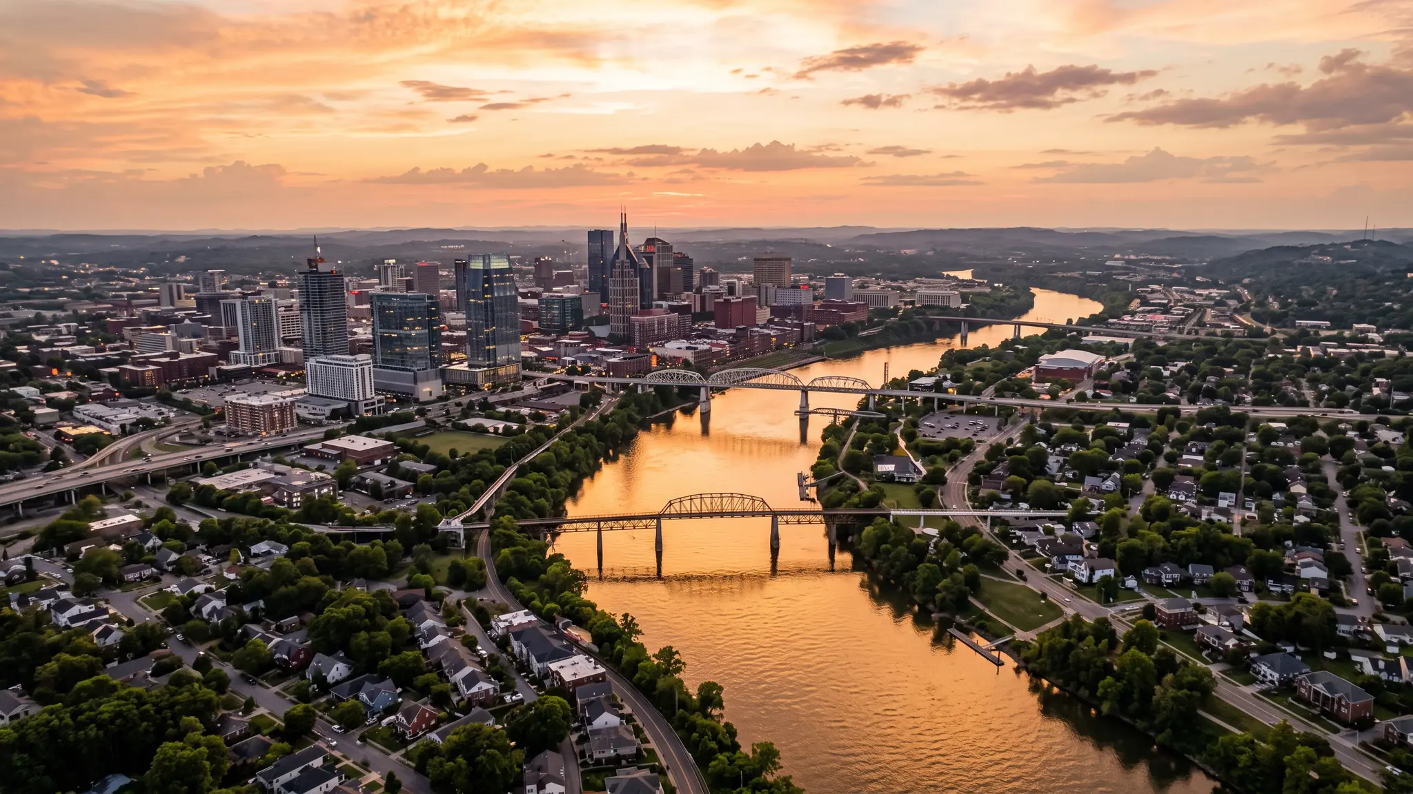 Aerial view of the Cumberland River winding past the Nashville skyline and Middle Tennessee farmland at sunset